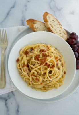 Spaghetti Carbonara with Bacon on a white bowl served with bread
