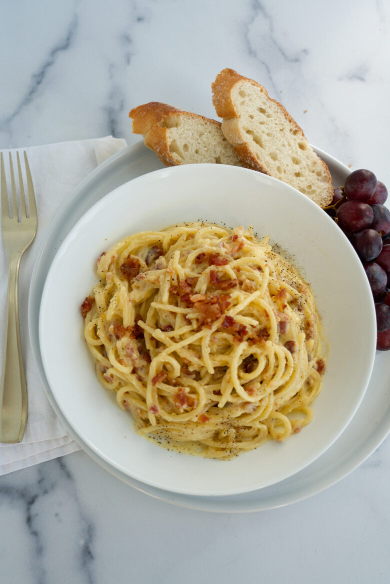 Spaghetti Carbonara with Bacon on a white bowl served with bread