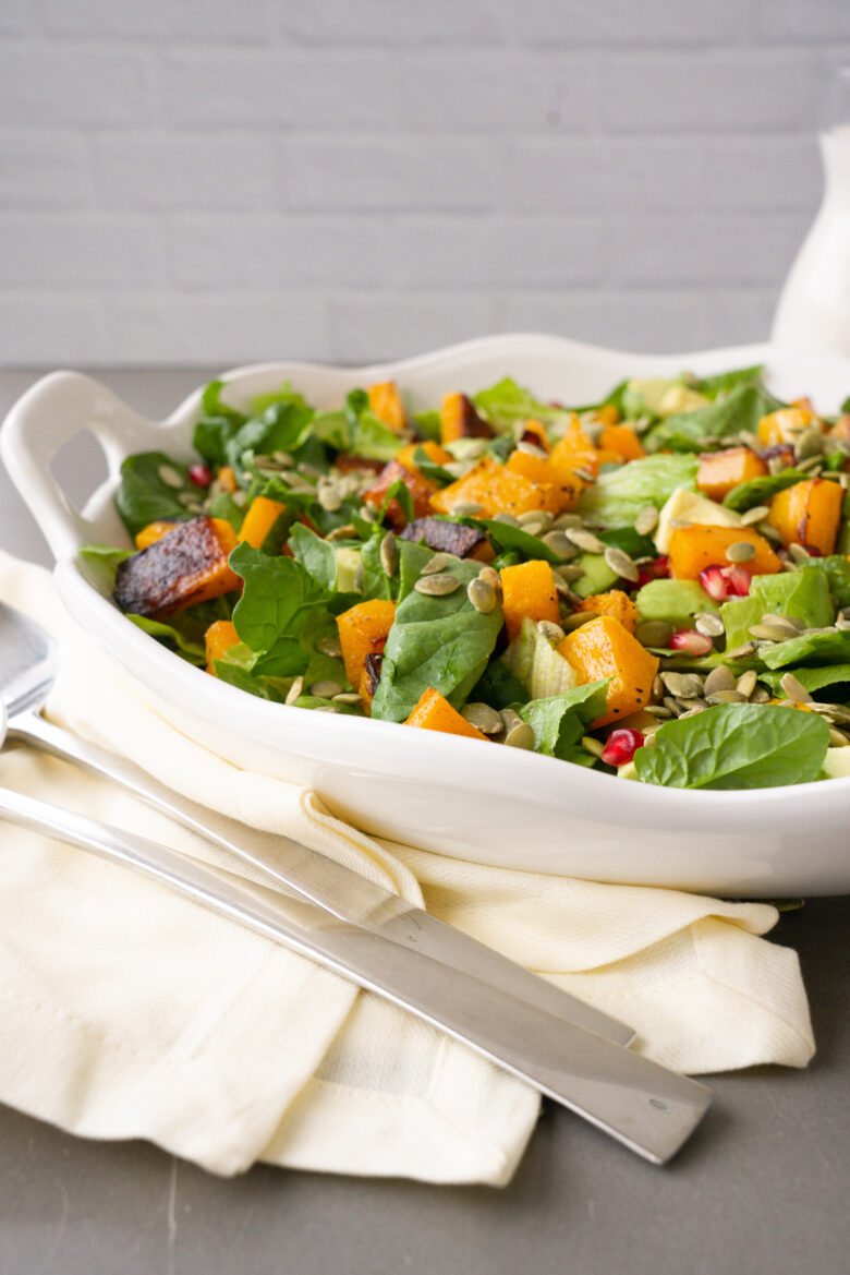 Harvest Salad with Buttermilk Sage Dressing on white serving platter with container of salad dressing