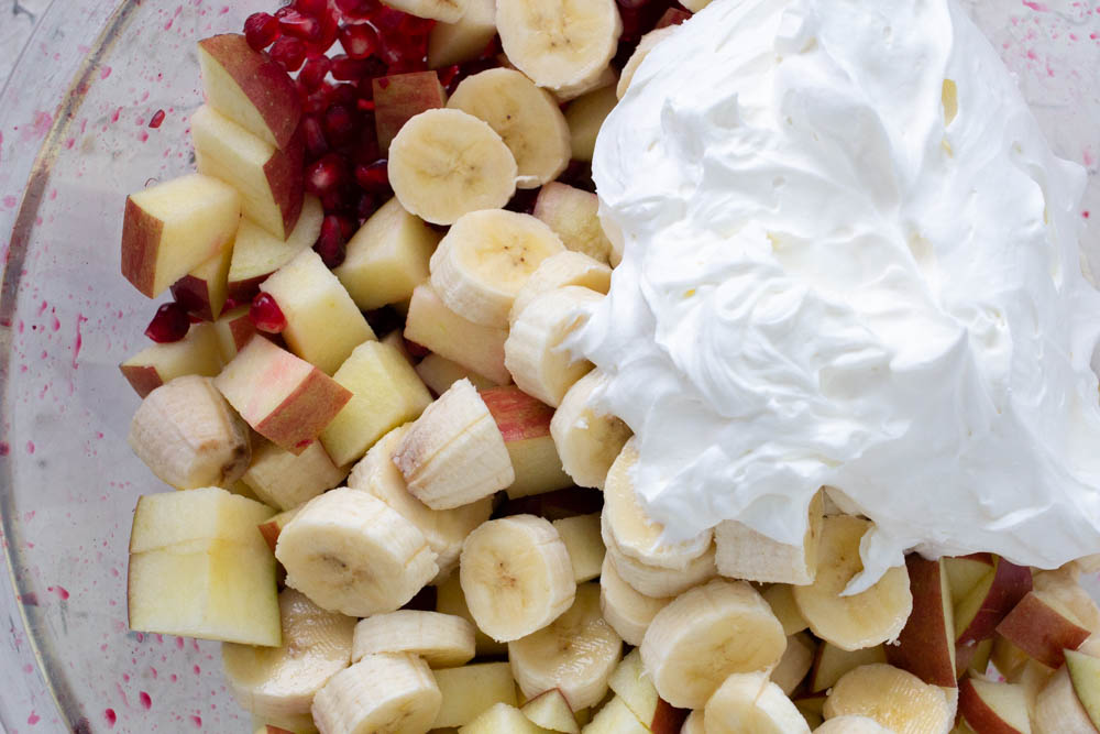 Apple, banana, pomegranate salad with whipped cream