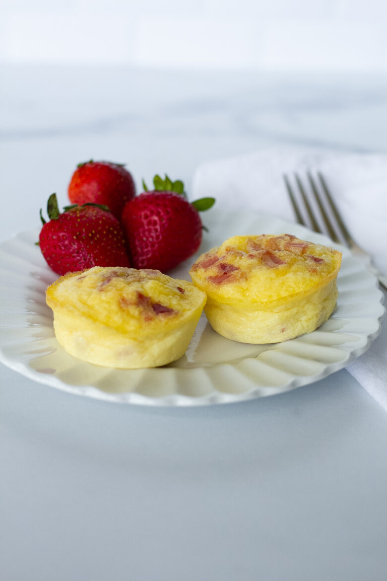 Gruyère and Bacon Egg Bites on white plate with strawberries