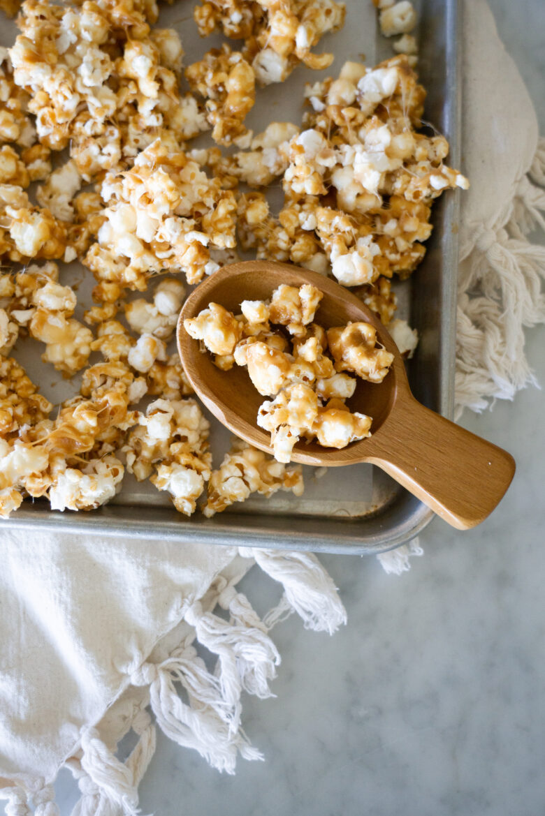 The Very Best Crunchy Caramel Corn on a pan with wooden scoop