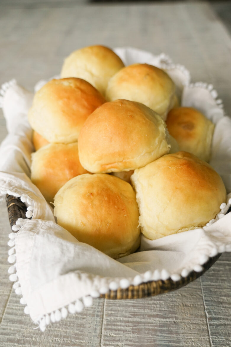 basket of potato rolls with off white napkin
