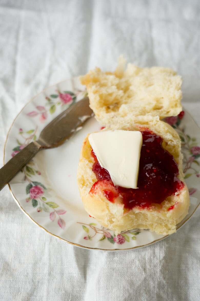 potato rolls on a plate with butter, butter knife and jelly