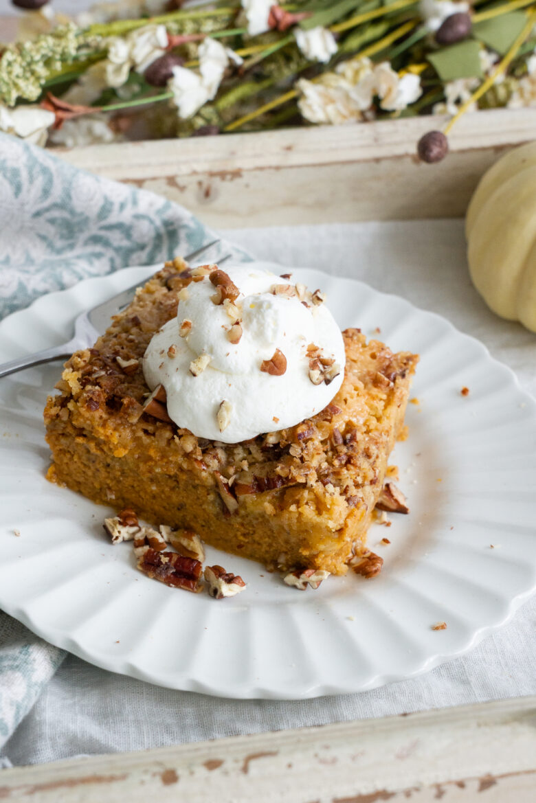 Pumpkin Dump Cake with whipped cream and nuts on white plate