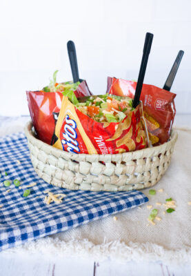 Three bags of Walking Tacos in a basket on blue and white checkered cloth.