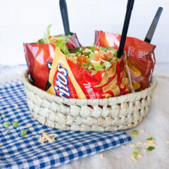 Three bags of Walking Tacos in a basket on blue and white checkered cloth.