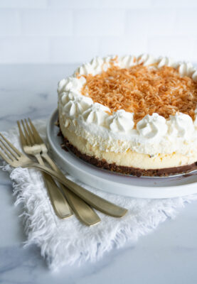 Better Than Cheesecake Factory Coconut Cheesecake with chocolate ganache layer on a white serving plate with gold forks.