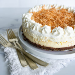 Better Than Cheesecake Factory Coconut Cheesecake with chocolate ganache layer on a white serving plate with gold forks.