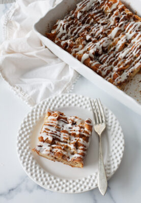 Overnight Cinnamon Roll Breakfast Casserole. One serving on a white plate with a fork.