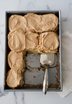 Maple Cinnamon Rolls in 9x13-inch pan being removed with serving utensil.